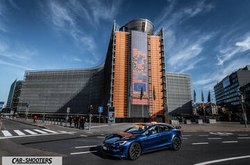Tesla Model S Plaid – front three-quarter, blue in front of a large modern building