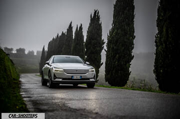 Polestar 2 – front three-quarter, silver on a wet road lined with trees