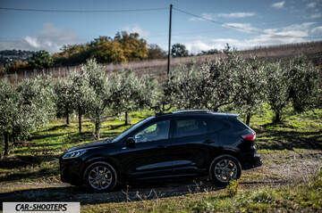 Ford Kuga STLine – side profile, black on a dirt road among trees