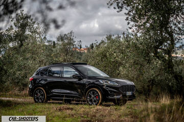 Ford Kuga STLine – front three-quarter, black on a dirt road among trees