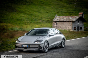 Hyundai Ioniq 6 – front three-quarter, silver on a road with a stone building