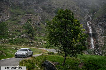 Hyundai Ioniq 6 – front three-quarter, silver on a mountain road with a waterfall background