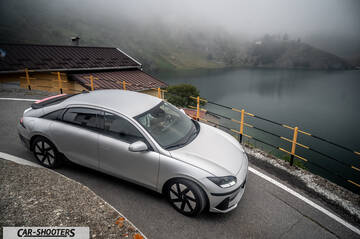 Hyundai Ioniq 6 – front three-quarter, silver on a mountain road by a lake