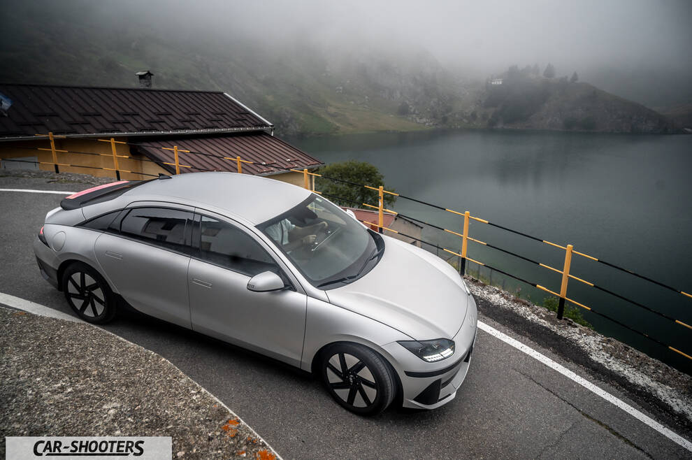 Hyundai Ioniq 6 – front three-quarter, silver on a mountain road by a lake