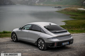 Hyundai Ioniq 6 – rear three-quarter, silver metallic on a road by a lake