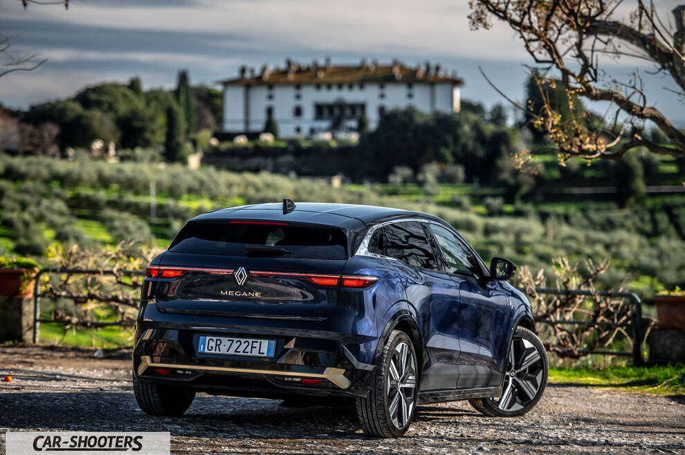 Renault Megane E TECH – rear three-quarter, dark blue against a rustic villa backdrop