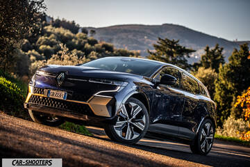 Renault Megane E TECH – front three-quarter, dark blue against a mountain backdrop