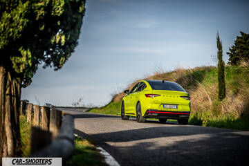 Skoda Enyaq – rear three-quarter, yellow on a winding country road