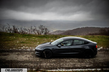 Tesla Model 3 2025 – side profile, dark grey against a mountain backdrop