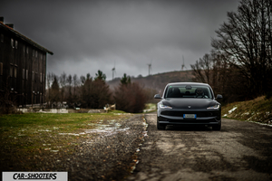 Tesla Model 3 2025 – front three-quarter, dark grey on a country road