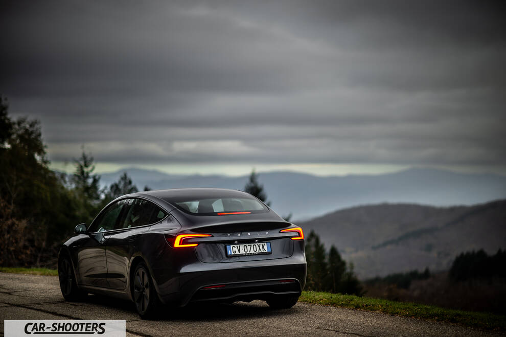 Tesla Model 3 2025 – rear three-quarter, dark grey against a mountain backdrop
