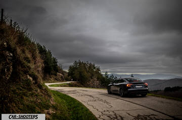 Tesla Model 3 2025 – rear three-quarter, dark grey on a winding mountain road