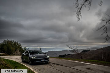 Tesla Model 3 2025 – front three-quarter, dark grey on a mountain road