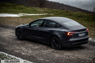Tesla Model 3 2025 – rear three-quarter, dark grey on a country road