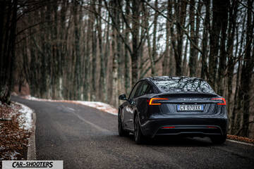 Tesla Model 3 2025 – rear view, dark grey on a winding forest road