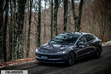 Tesla Model 3 2025 – front three-quarter, dark grey metallic on a country road