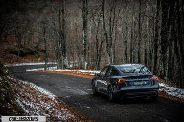Tesla Model 3 2025 – rear three-quarter, dark grey on a snowy winding road