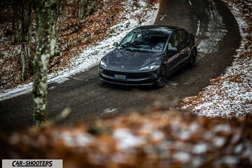 Tesla Model 3 2025 – front three-quarter, dark grey on a snowy winding road