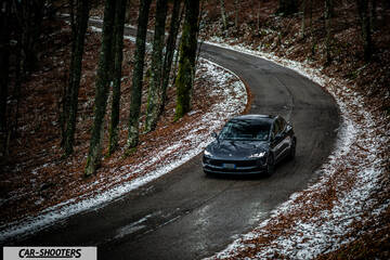 Tesla Model 3 2025 – front three-quarter, dark grey on a winding snowy road