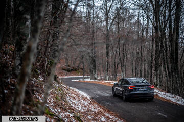 Tesla Model 3 2025 – rear three-quarter, dark grey on a winding forest road