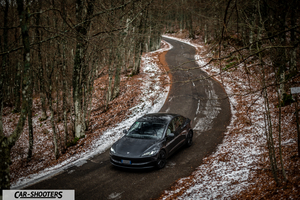 Tesla Model 3 2025 – front three-quarter, grey metallic on a winding winter road