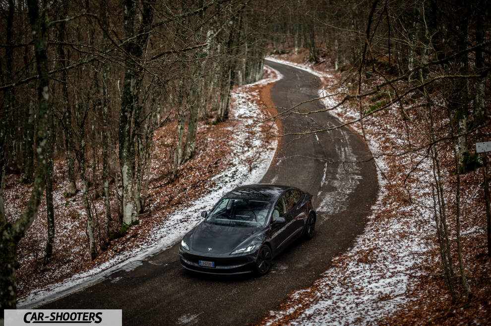 Tesla Model 3 2025 – front three-quarter, grey metallic on a winding winter road
