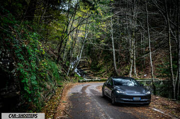 Tesla Model 3 2025 – front three-quarter, dark grey on a forest road