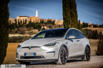 Tesla Model X – front three-quarter, silver against a historic village backdrop