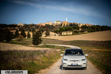Tesla Model X – front three-quarter, white on a country road with a hilltop town backdrop