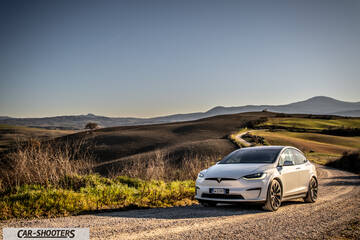 Tesla Model X – front three-quarter, white on a dirt road with rolling hills