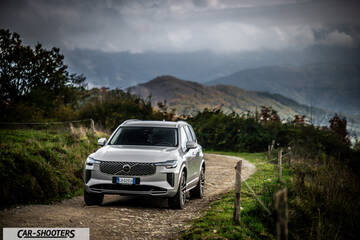 Volvo XC90 2025 – front three-quarter, silver on a dirt road with mountains