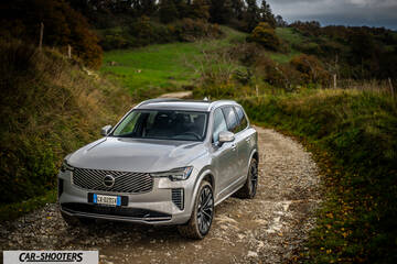Volvo XC90 2025 – front three-quarter, silver metallic on a country road