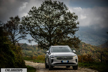 Volvo XC90 2025 – front three-quarter, silver metallic on a country road