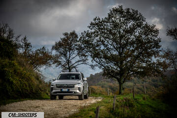 Volvo XC90 2025 – front three-quarter, silver metallic on a country road