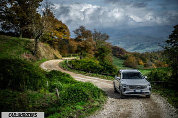 Volvo XC90 2025 – front three-quarter, silver metallic on a country road