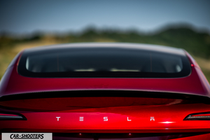 Tesla Model 3 Performance – rear view, red metallic against a blurred outdoor backdrop