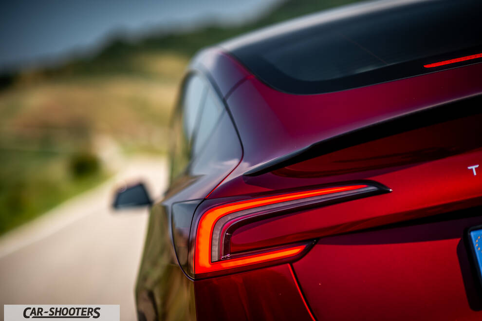 Tesla Model 3 Performance – rear three-quarter, red metallic on a country road