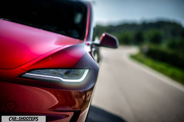 Tesla Model 3 Performance – front three-quarter, red on a country road