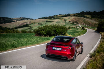Tesla Model 3 Performance – rear three-quarter, dark red metallic on a country road