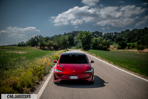 Tesla Model 3 Performance – front three-quarter, red metallic on a country road
