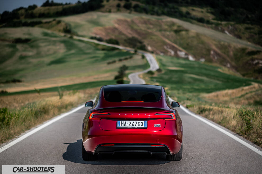 Tesla Model 3 Performance – rear view, red metallic on a winding country road