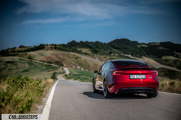Tesla Model 3 Performance – rear three-quarter, red metallic on a country road