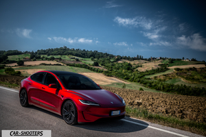 Tesla Model 3 Performance – front three-quarter, red metallic on a country road