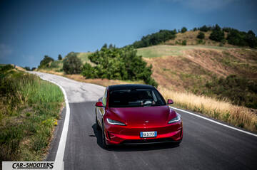Tesla Model 3 Performance – front three-quarter, red metallic on a winding country road