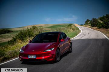 Tesla Model 3 Performance – front three-quarter, red on a winding country road