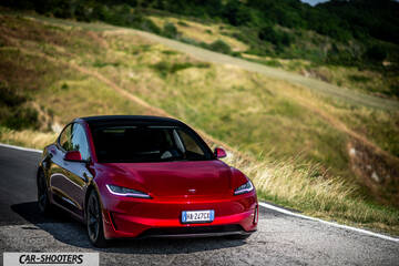 Tesla Model 3 Performance – front three-quarter, red on a winding country road